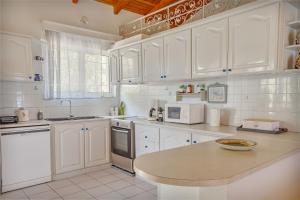 卡拉马孔Heliotropio的厨房配有白色橱柜和台面