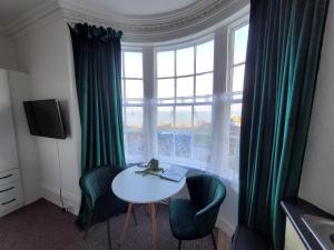 斯卡伯勒SeaView ground floor flat fast WiFi & FREE PARKING的客房设有桌椅和大窗户。
