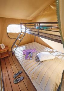 AscaratCamping Europ'Camping - Maeva的木地板上的一张双层床,配有一双鞋