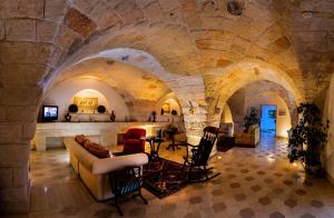 佩兹迪格雷科马塞里亚瑞莱斯卡尔迪纳莱酒店的石头建筑中一间带沙发和椅子的客厅