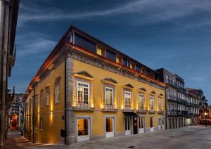 波尔图Pousada do Porto - Rua das Flores的街道上一座黄色建筑,设有白色窗户