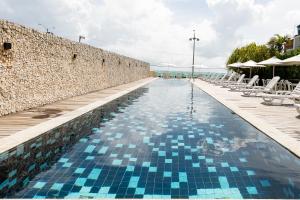 纳塔尔纳塔尔牦牛海滩酒店的蓝色瓷砖的石墙旁的游泳池