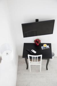 圣马里纳萨利纳B&B La Palma的一张带白色椅子的黑色书桌和一台电视机
