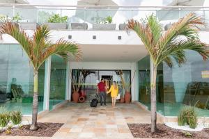 纳塔尔纳塔尔牦牛海滩酒店的走在棕榈树建筑中的男人和女人