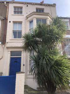 斯卡伯勒Granby House Holiday Apartments, Apartment 2, Formerly Sandy Palms的一座带蓝色门和棕榈树的房子