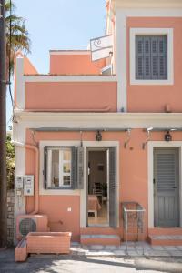 AnemómylosWell Apartments by Skyloft Corfu的粉红色的房子,有窗户和门