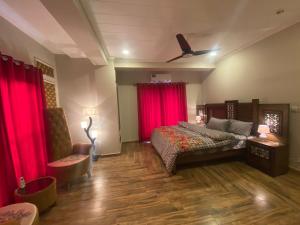 拉瓦尔品第De-Meridian Luxury Apartments的一间卧室配有红色窗帘、一张床和风扇