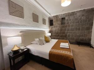 库斯科Katari at Plaza de Armas Cusco的一间卧室配有床、灯和砖墙