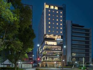 四日市Comfort Hotel Yokkaichi的一座高大的建筑,晚上在城市里亮着灯
