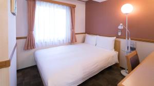 熊本Toyoko Inn Kumamoto-jyo Toricho Suji的酒店客房设有白色的床和窗户。
