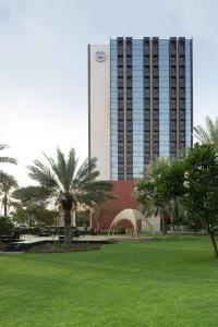 马斯喀特阿曼喜来登酒店的一座高大的建筑,在公园里种有棕榈树