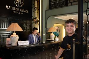 河内Madelise Palace Hotel & Spa的站在旅馆柜台前的人