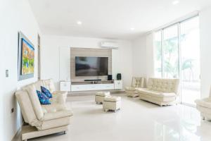 圣玛尔塔Casa finca con piscina的客厅配有白色家具和平面电视