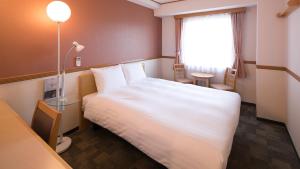 藤枝Toyoko Inn Shizuoka Fujieda eki Kita guchi的酒店客房设有白色的床和窗户。