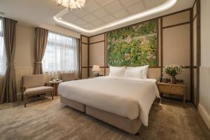 河内La Passion Hanoi Hotel & Spa的卧室配有一张大床,墙上挂有绘画作品
