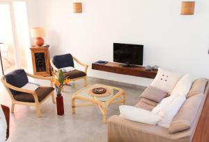 圣皮埃尔Les Patios de Grands Bois的客厅配有沙发、椅子和电视