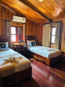 琅勃拉邦Khounphet Heritage House的一间卧室设有两张床、一张桌子和两个窗户。