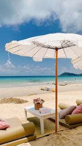 沙美岛Kerala Coco Resort的海滩上的白色遮阳伞,配有椅子和桌子