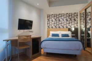圣塞瓦斯蒂安斯考特而科迪纳酒店的一间卧室配有一张床、一张书桌和一台电视。