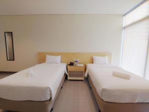 马尼拉Kaizen Suites的带窗户的客房内设有两张单人床。