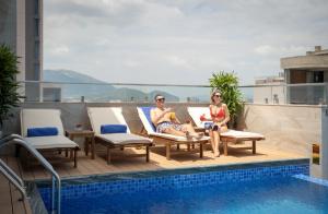 芽庄Maris Hotel Nha Trang的两人坐在游泳池旁的甲板上