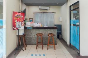 雅加达RedDoorz Plus near Universitas Indonesia的餐厅内的厨房设有两张凳子和柜台