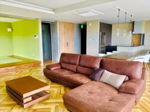 冲绳岛市CONDOMINIUM 紅-BIN-的客厅配有棕色皮沙发和桌子