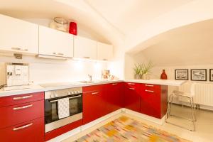 萨尔茨堡Sound of Music World Appartement的厨房配有红色橱柜和白色柜台。