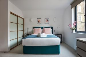 伦敦Hammersmith Mews by Viridian Apartments的一间卧室配有蓝色的床和粉红色枕头