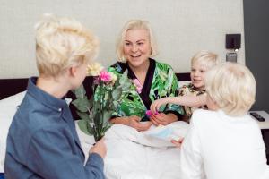 赫尔辛基克劳斯K酒店的一名妇女,与两个孩子一起坐在医院的床上