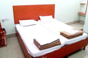 瓦拉纳西Goroomgo Kashi Inn Varanasi Near Railway Station的一张铺有白色床单的床和木制床头板
