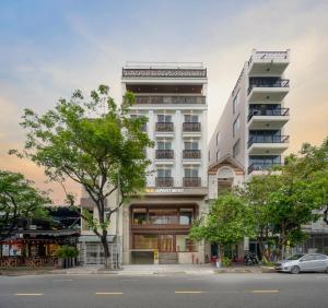 岘港MK Riverside Apartment by Haviland的一座高大的白色建筑,前面有树木