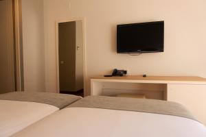 奇皮奥纳Hotel Vértice Chipiona Mar的酒店客房配有一张床和一张书桌及一台电视