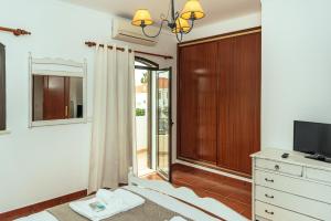 阿尔图拉Altura Beach Villa by GT House的一间卧室配有一张床、一台电视和一个梳妆台