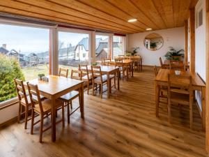 科热诺夫Chata u kostela的餐厅设有木桌和椅子以及大窗户。