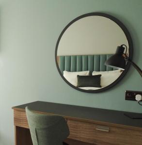 特尔福德假日特尔福德铁桥酒店的一张桌子上方墙上的镜子和一张床位