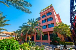 乌隆他尼Amman Unique Hotel - SHA Plus的前面有棕榈树的粉红色建筑