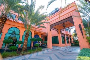 乌隆他尼Amman Unique Hotel - SHA Plus的一座种植了棕榈树的橙色建筑