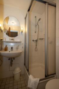 施朗根巴特Hotel Schlangenbader Hof的带淋浴、盥洗盆和浴缸的浴室