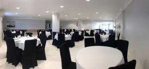 阿罗萨新镇布兰多明酒店的用餐室配有白色桌子和黑色椅子