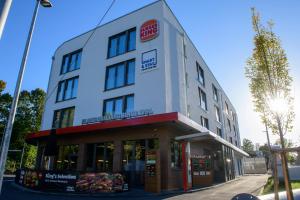 萨尔布吕肯Smart & Stay Aparthotel Saarbrücken Süd - Self-Check-In - Free Parking的大街上一座白色的大建筑,有商店