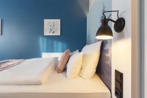 埃森Yggotel Solsort的一间卧室拥有蓝色的墙壁,配有一张带枕头的床。