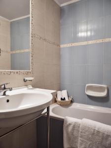 阿凯松Windmill Hotel的浴室配有盥洗盆、浴缸和盥洗盆