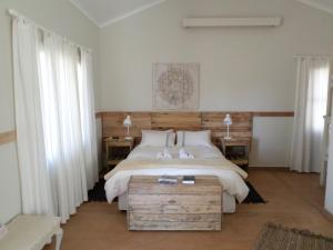 温特和克Out Of Nature Country Lodge的一间卧室设有一张大床、两张桌子和两个窗户。