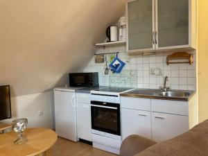 达默An der Aue 15 Wohnung Ley的一间配备有白色家电和桌子的小厨房