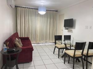 巴雷里尼亚斯Gran Lençóis Flat Residence的客厅配有红色的沙发和玻璃桌