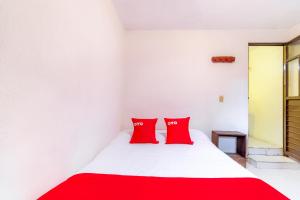 圣克里斯托瓦尔-德拉斯卡萨斯OYO Hotel La Luna的卧室配有带红色枕头的白色床