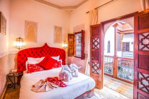 马拉喀什梅尔霍恩摩洛哥传统庭院旅馆及Spa的一间卧室配有红色的床,上面有鞋子