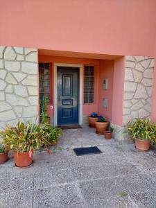 SapatariaCasa Susana的粉红色建筑中一扇蓝色门,里面栽有盆栽植物