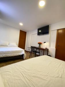 基多HOSTAL COMFORT- INN by BRILLIANT的酒店客房设有两张床和一张书桌及电视